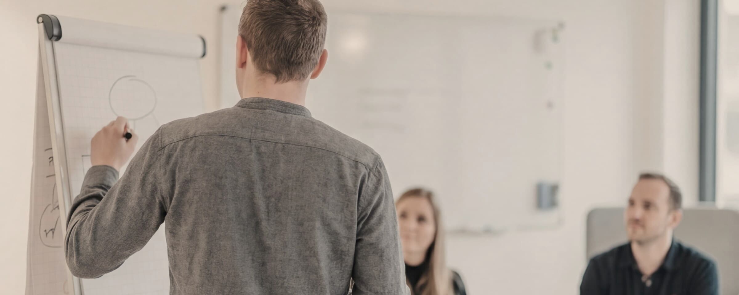 Benjamin werkt samen met twee collega’s aan een proces op een flipchart